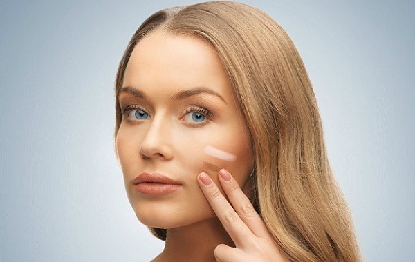 bright picture of beautiful woman applying foundation.